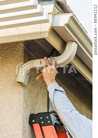 Worker Attaching Aluminum Rain Gutter and Down Spout Worker Attaching Aluminum Rain Gutter and Down Spout 66942212