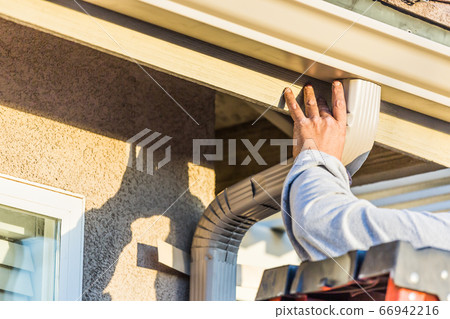 Worker Attaching Aluminum Rain Gutter and Down Spout 66942216