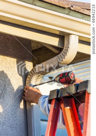 Worker Attaching Aluminum Rain Gutter and Down Spout 66942218