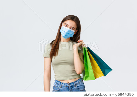 Social distancing, coronavirus and shopping, fashion concept. Cute young stylish woman in medical mask buying summer clothes, wear protective equipment during coronavirus pandemic 66944390