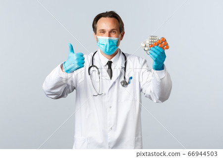 Covid-19, preventing virus, healthcare workers and vaccination concept. Satisfied handsome doctor smiling, wear medical mask and gloves, thumb-up as recommend pills, show good medication Covid-19, preventing virus, healthcare workers and vaccination concept. Satisfied handsome doctor smiling, wear medical mask and gloves, thumb-up as recommend pills, show good medication 66944503