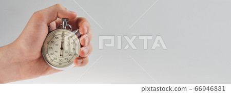 hand holding a stopwatch on a gray background 66946881