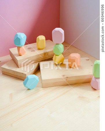 Abstract figures from elements of wooden tumi ishi pastel colors on a wooden podium on a paper background. Abstract figures from elements of wooden tumi ishi pastel colors on a wooden podium on a paper background. 66946996