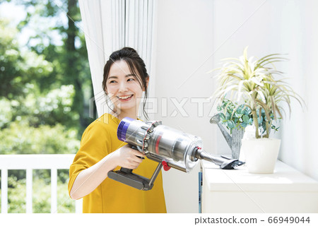 Young woman vacuum cleaner 66949044