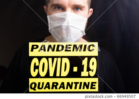 Coronavirus, quarantine, covid-19 and pandemic concept. Sad and sick man of corona virus looking through the window. Stay at home. 66949507