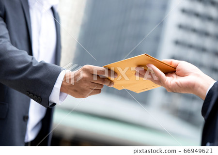 Businessman hand recieving yellow envelope from boss in urban city 66949621