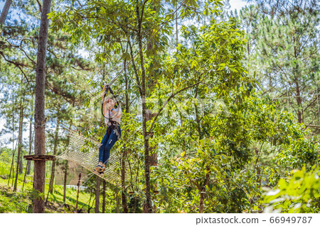 Young attractive woman in adventure rope park in safety equipment Young attractive woman in adventure rope park in safety equipment 66949787