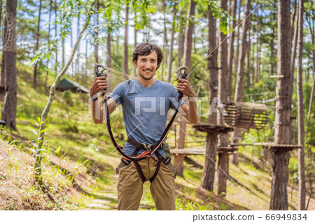 Young attractive man in adventure rope park in safety equipment Young attractive man in adventure rope park in safety equipment 66949834