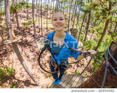 Young attractive woman in adventure rope park in safety equipment Young attractive woman in adventure rope park in safety equipment 66950048