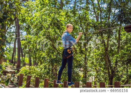 Young attractive woman in adventure rope park in safety equipment 66950158