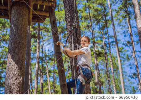 Young attractive woman in adventure rope park in safety equipment Young attractive woman in adventure rope park in safety equipment 66950430