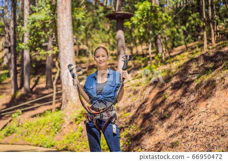 Young attractive woman in adventure rope park in safety equipment 66950472