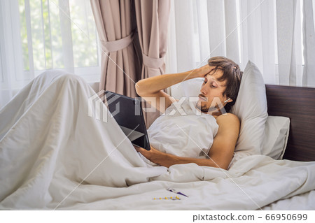 Male patient is sick while lying in his bed and calls an online doctor through a gadget 66950699