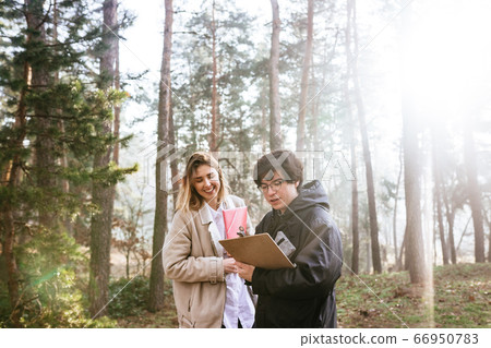 Scientists are studying plant species and inspect trees in the forest. Scientists are studying plant species and inspect trees in the forest. 66950783