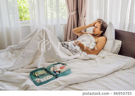 Male patient is sick while lying in his bed and calls an online doctor through a gadget 66950785