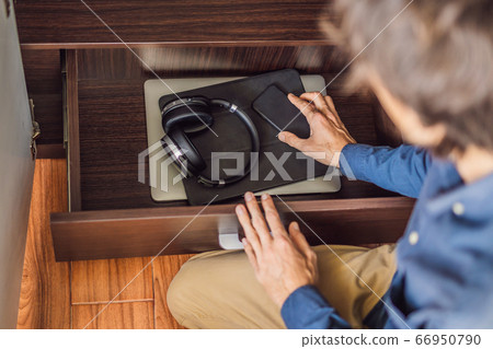 A man puts gadgets in a cabinet for digital detox 66950790
