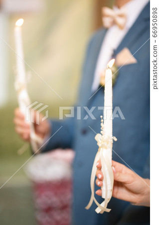 Bride and groom holding candles in church 66950898
