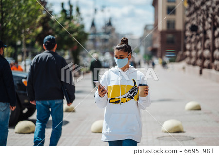 Young woman holding coffee wearing protective medical mask Young woman holding coffee wearing protective medical mask 66951981