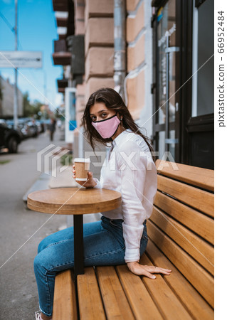 Woman in a medical mask drinks coffee on the street 66952484