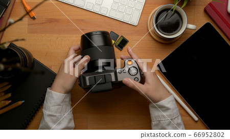 Female freelancer holding digital camera on wooden 66952802