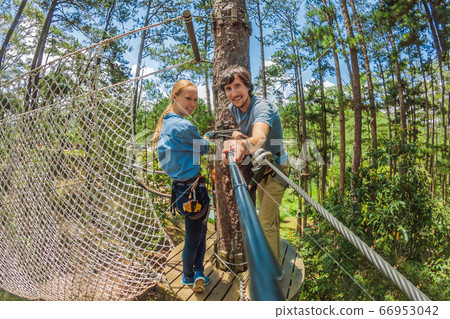 Young attractive man and woman in adventure rope park in safety equipment 66953042