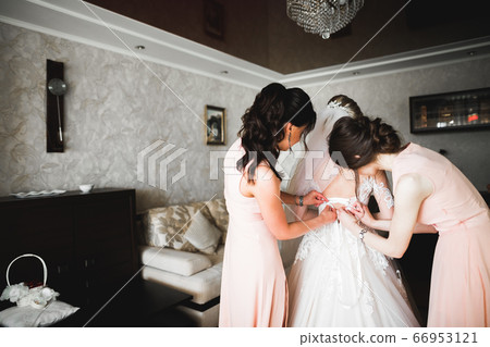 Hands of bridesmaids on bridal dress. Happy marriage and bride at wedding day concept 66953121