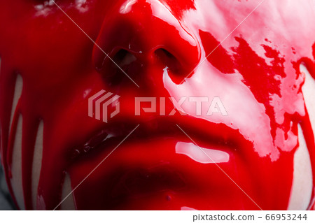 Image of a female's face with spreading glossy red paint 66953244