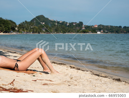 Beautiful slim women's legs on the beach. Lower half of the girl body lying on the beach by the sea. Young women's wet and sun-tanned legs on the beach with the sea view. Beautiful slim women's legs on the beach. Lower half of the girl body lying on the beach by the sea. Young women's wet and sun-tanned legs on the beach with the sea view. 66955003