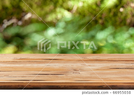 Aged wooden table for montage or display products on a green leaves blurred background. Aged wooden table for montage or display products on a green leaves blurred background. 66955038