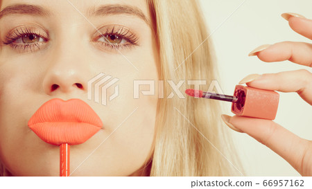Woman applying lipstick or lip gloss Woman applying lipstick or lip gloss 66957162