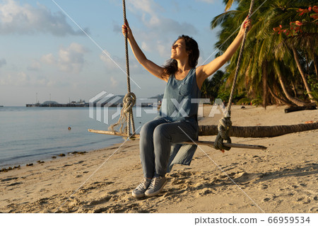 The girl on the beach rides on a swing during 66959534