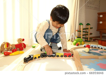 Boy playing with a wooden train 66959848
