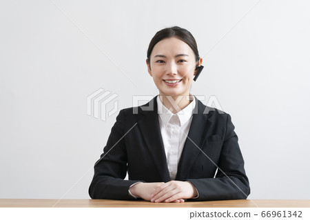 A young woman in a suit wearing a headset and talking from the camera's perspective A young woman in a suit wearing a headset and talking from the camera's perspective 66961342