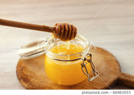 Honey dripping from a wooden dipper in jar on old 66963055