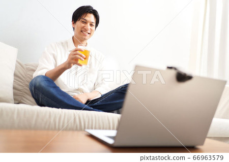 一個男人一邊看著電腦屏幕一邊喝酒 66963579
