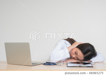 Young Asian woman doctor sitting on desk, she look Young Asian woman doctor sitting on desk, she look 66965275