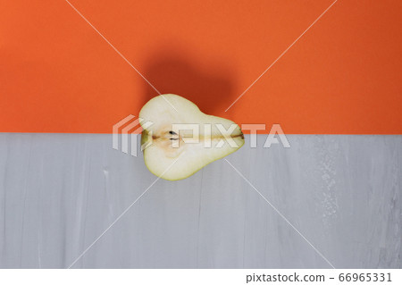 Over ripe half green delicious pear against orange and grey background. Design template, organic concept Over ripe half green delicious pear against orange and grey background. Design template, organic concept 66965331