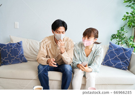 男人和女人在客廳裡戴口罩以採取措施防止感染和放鬆 66966285