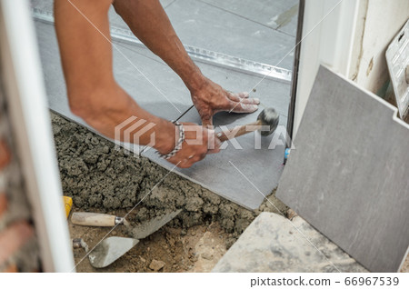 Hand of tiler laying and use mallet knocking Hand of tiler laying and use mallet knocking 66967539