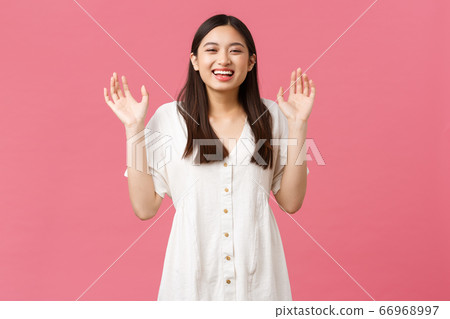 Beauty, people emotions and summer leisure concept. Happy smiling asian girl laughing and showing empty hands, raise arms and giggle, having fun over pink background Beauty, people emotions and summer leisure concept. Happy smiling asian girl laughing and showing empty hands, raise arms and giggle, having fun over pink background 66968997
