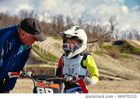 kids riding at motobike, junior competition on motorcycle. Coach gives instructions to his young rider kids riding at motobike, junior competition on motorcycle. Coach gives instructions to his young rider 66970150