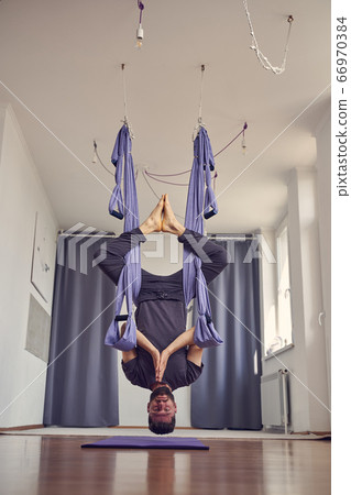 Bearded man hanging upside down and doing prayer pose 66970384