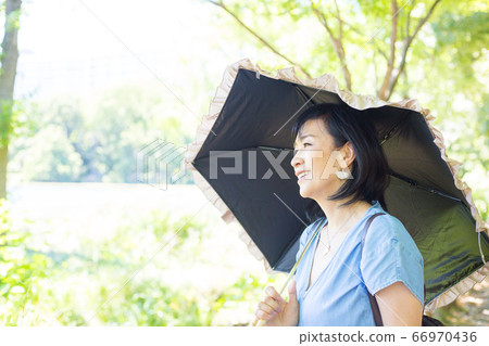 帶著陽傘散步的中年婦女帶著陽傘散步的中年婦女 帶著陽傘散步的中年婦女帶著陽傘散步的中年婦女 66970436
