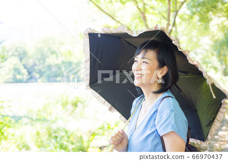 帶著陽傘散步的中年婦女帶著陽傘散步的中年婦女 帶著陽傘散步的中年婦女帶著陽傘散步的中年婦女 66970437