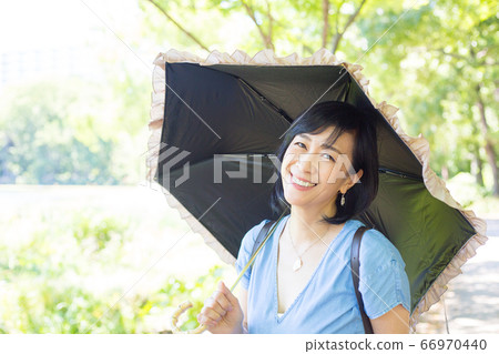 帶著陽傘散步的中年婦女帶著陽傘散步的中年婦女 66970440