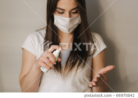Young woman in white t-shirt and mask use sanitizer Young woman in white t-shirt and mask use sanitizer 66970842