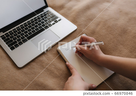 Top view of woman on the bed using laptop and writing down in notebook. Covid-19 Top view of woman on the bed using laptop and writing down in notebook. Covid-19 66970846