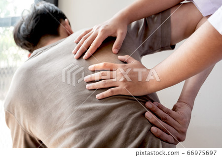 Female physiotherapists provide physical assistance to male patients with back injuries back massages for relaxation and muscle recovery in the rehabilitation center 66975697