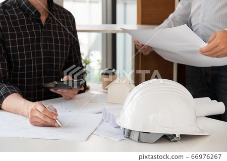 A team of confident architects working together in the office talking about construction and home design projects A team of confident architects working together in the office talking about construction and home design projects 66976267