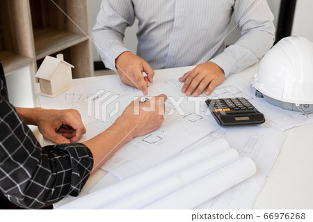 A team of confident architects working together in the office talking about construction and home design projects A team of confident architects working together in the office talking about construction and home design projects 66976268